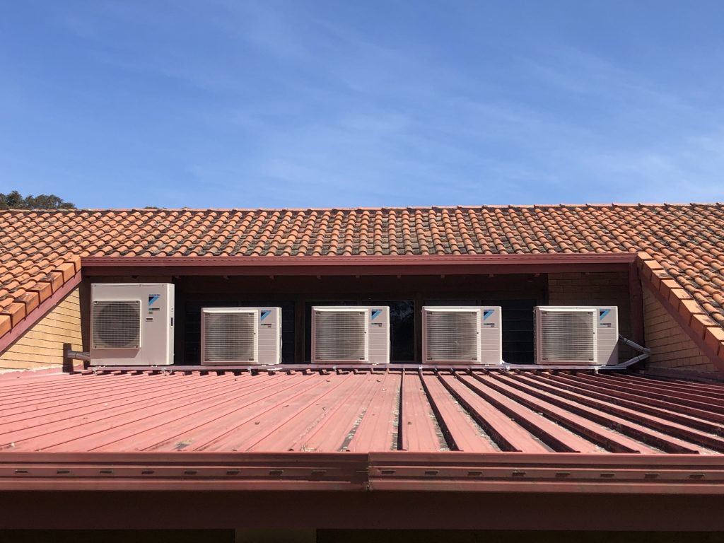 Five air conditioning outdoor units mounted on roof of school